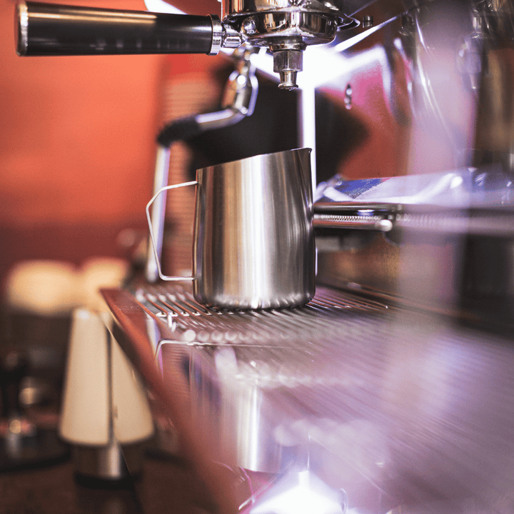 milk pitcher on an espresso machine in a coffee shop