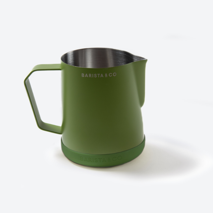 An olive green stainless steel milk pitcher with a matching green handle and base, featuring the BARISTA & CO logo, on a clean white background.