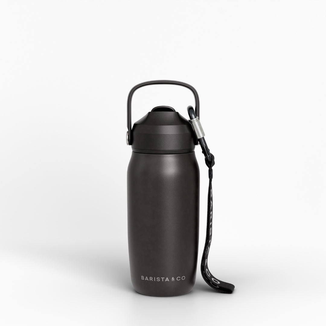 A matte black insulated water bottle with a carrying loop and wrist strap, featuring the BARISTA & CO logo near the base, set against a clean white background.