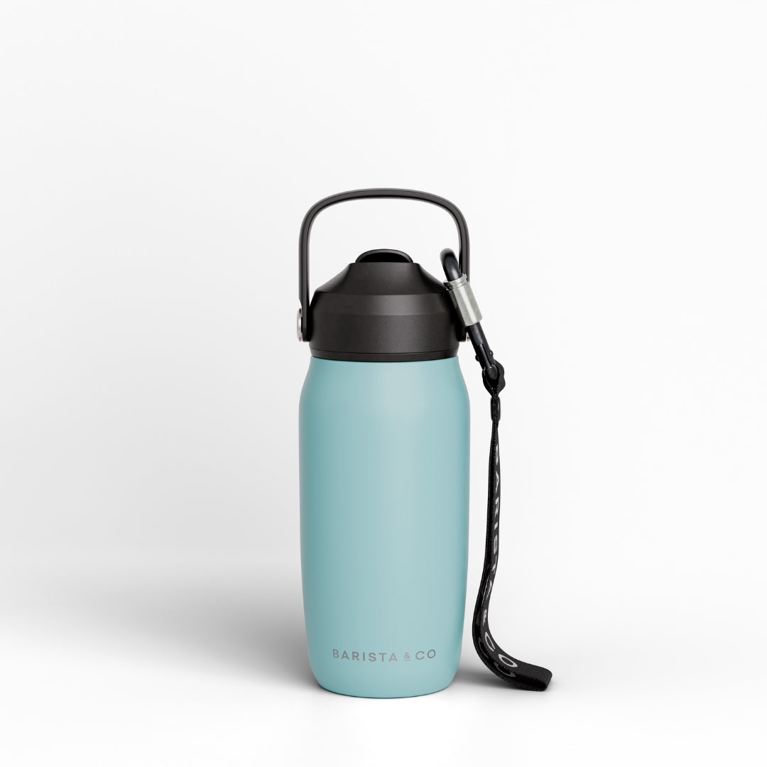 A light blue insulated water bottle with a black lid, carrying loop, and black wrist strap, shown on a clean white background. The brand name 'BARISTA CO' is printed near the bottom.