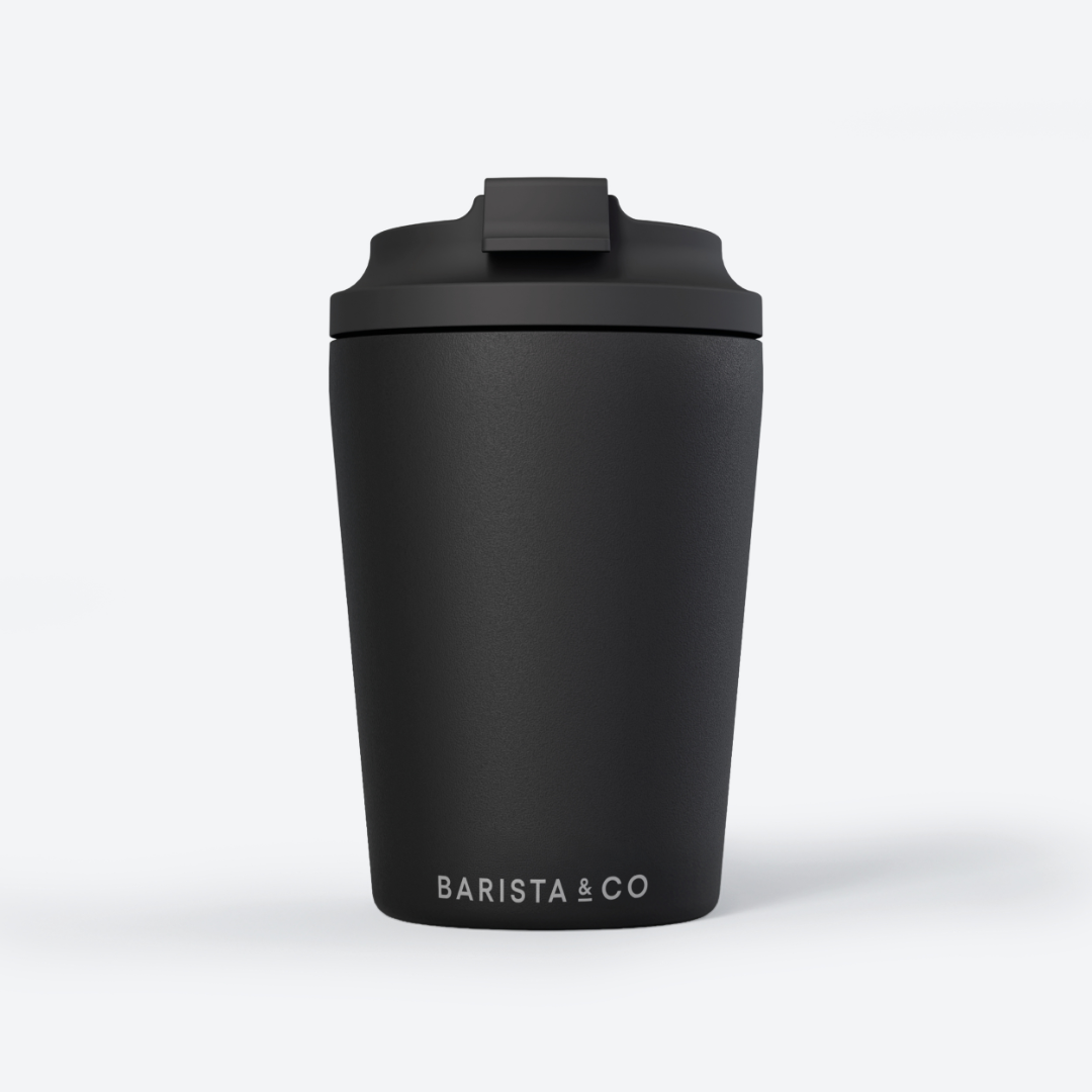 A matte black travel tumbler with a matching black lid and the white text 'BARISTA & CO' printed near the bottom, shown on a clean white background.