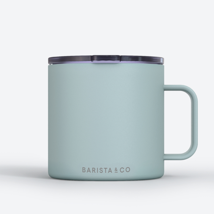 A light blue insulated mug with a dark translucent lid and a white handle, featuring the BARISTA & CO logo printed in gray near the bottom, set against a clean white background.