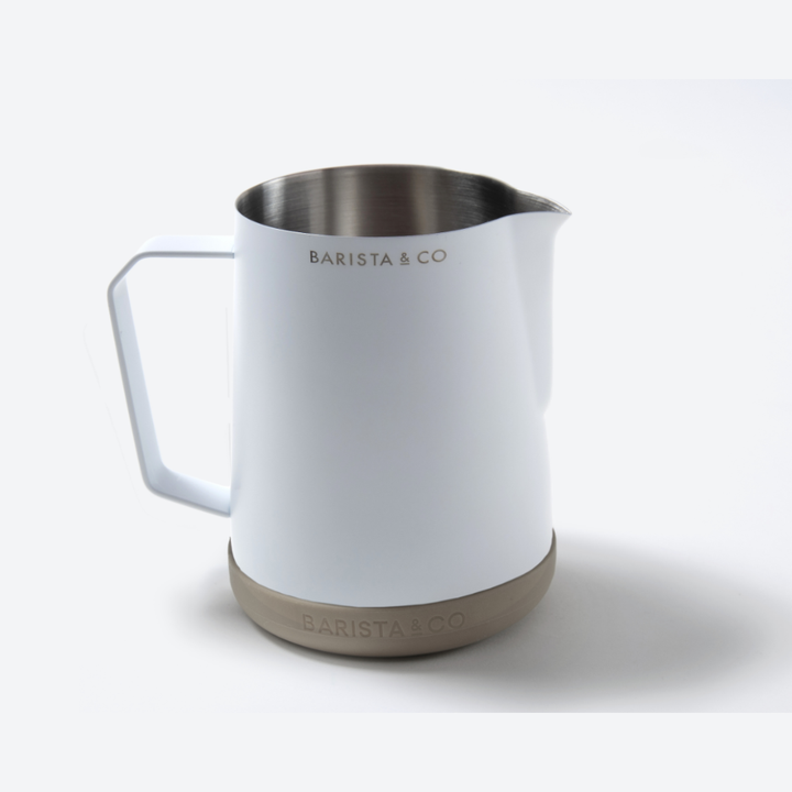 A white Barista & Co milk pitcher with a stainless steel interior and a beige textured base, shown on a clean white background.