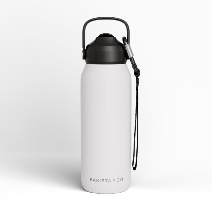 A matte white insulated water bottle with a black screw-on lid, carrying loop, and wrist strap, shown on a clean light gray background. The brand name 'BARISTA & CO' is printed near the bottom.