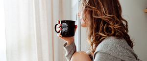 woman looking out window drinking coffee